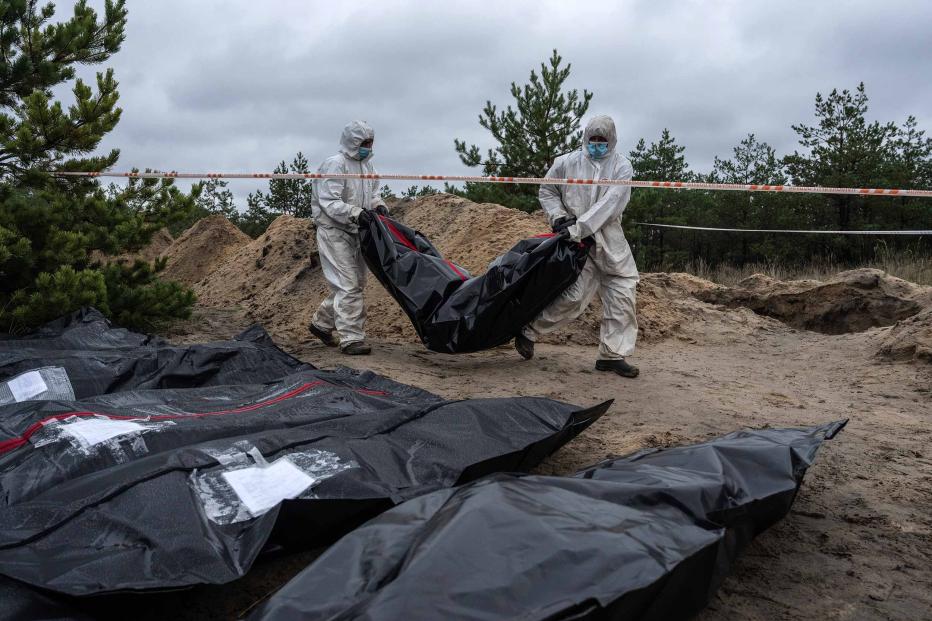 Forensic investigators remove an exhumed body from what is believed to be a mass grave on October 11, 2022 in Lyman, Donetsk oblast, Ukraine.