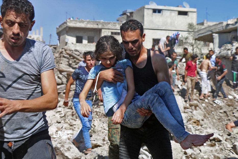 A man carries a child rescued from rubble after Syrian regime and Russian air strikes in the rebel-held town of Nawa in southern Syria on June 26, 2018.