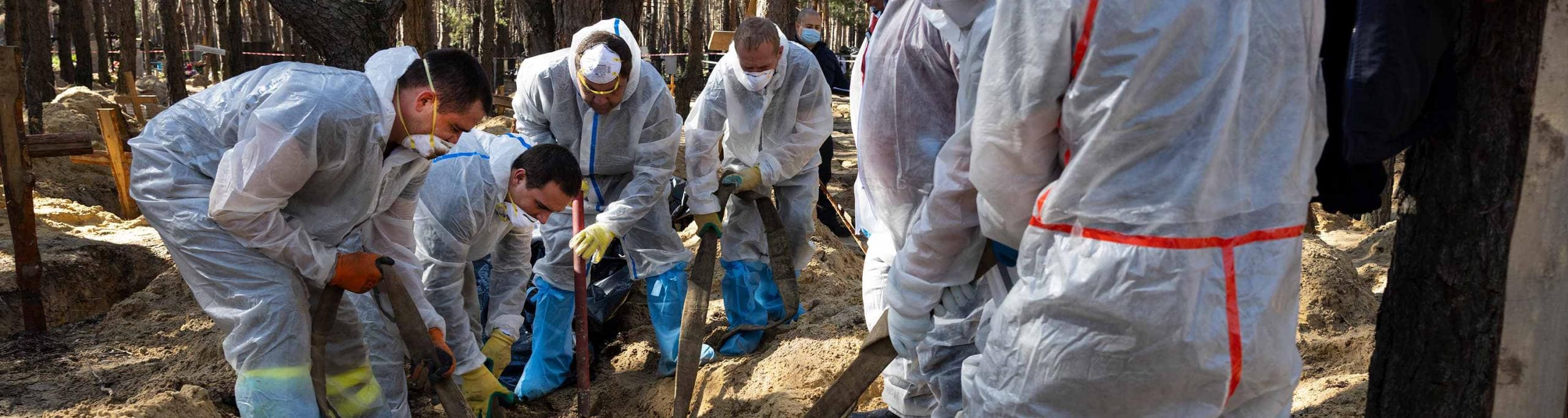 Rescue workers and forensic police exhume bodies from unidentified makeshift graves at the Pishanske cemetery on September 21, 2022 in Izium, Ukraine. The bodies will be examined by forensic officials for possible war crimes.