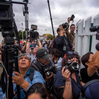 Journalists try to photograph members of a caravan of Central Americans who spent weeks traveling across Mexico as they walk towards the U.S. side of the border to ask authorities for asylum on April 29, 2018 in Tijuana, Baja California Norte, Mexico.