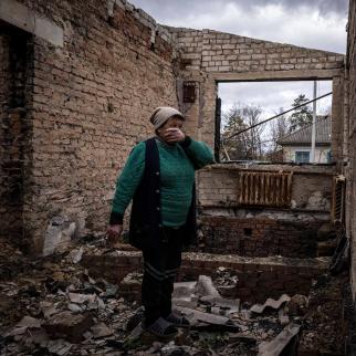 A woman picks up ornaments as she walks through her home that was destroyed during battles at the start of Russia's full scale invasion, in Yahidne village on October 30, 2022 in Chernihiv, Ukraine.