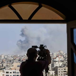 An AFPTV cameraman films while smoke plumes billow during Israeli air strikes in Gaza City on October 12, 2023 as raging battles between Israel and the Hamas movement continue for the sixth consecutive day. Thousands of people, both Israeli and Palestinians have died since October 7, 2023, after Palestinian Hamas militants based in the Gaza Strip, entered southern Israel in a surprise attack leading Israel to declare war on Hamas in Gaza on October 8.