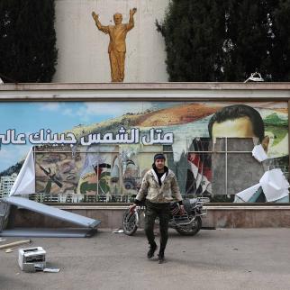 A man is pictured in front of a vandalised political banner featuring a portrait of Bashar al-Assad, following news the Syrian government regime had fallen on, December 8, 2024 in Damascus, Syria. 