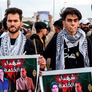 Protesters wearing bandages crossing their mouths stand holding up signs showing the faces of two slain journalists captioned in Arabic "martyrs of the word" during an anti-government demonstration, also calling for freedom of the press, in the southern Iraqi city of Basra on January 17, 2020.