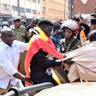 Plain clothed and uniformed security operatives arrest Sammy Okanya (C) in Kampala on July 23 2024.