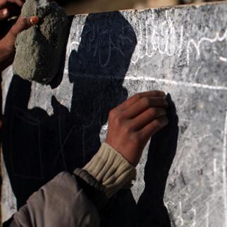 An Afghan boy writes on a chalkboard at a rural school in Afghanistan. (Photo: Spencer Platt/Getty Images)