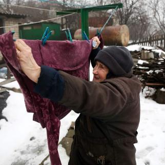 Lyudmila Kudelya, 73, hangs laundry near the ruins of her son's house, which burned down after a 120-mm mine hit their yard in February 2017. (February 3, 2022)