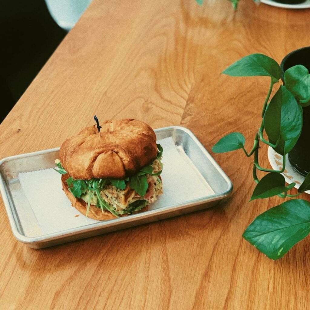 a breakfast sandwich with fresh greens on a wood table