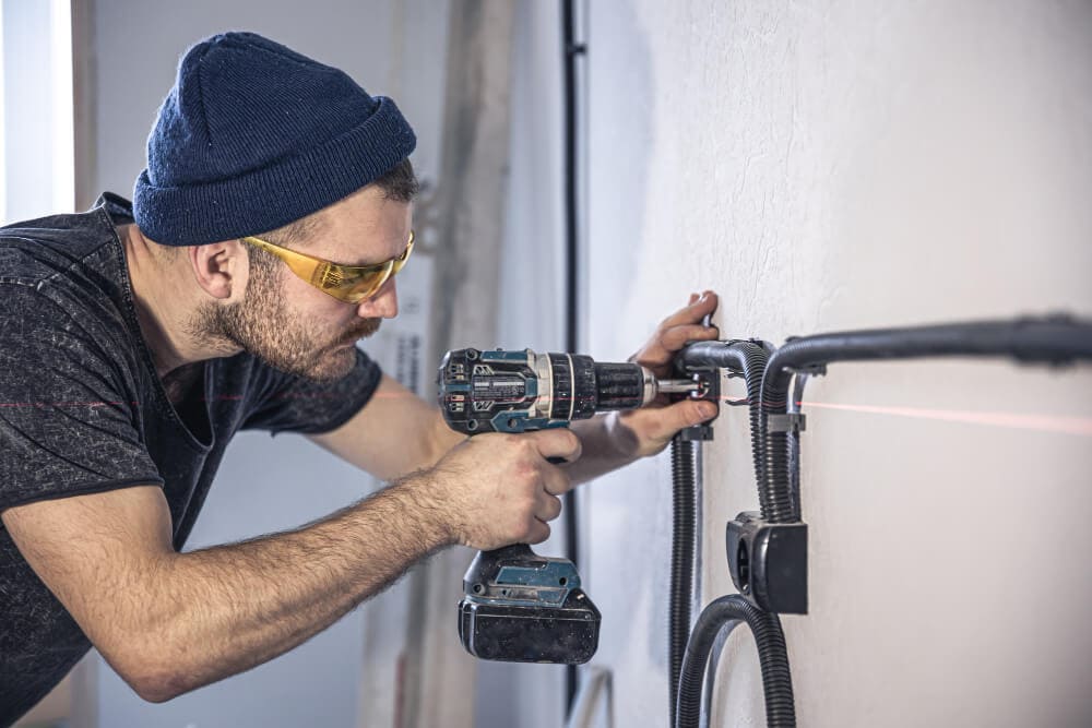  Electrician Is Mounting Electric Sockets On The White Wall Indoors