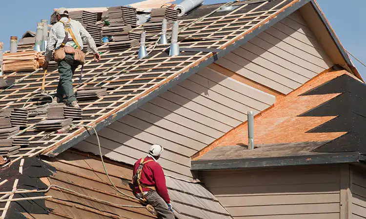 Full roof replacement in progress with workers removing old shingles