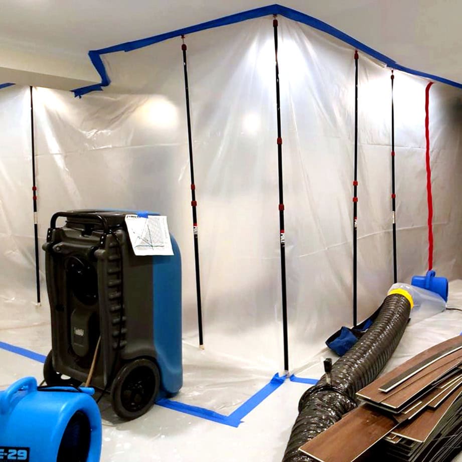 Technician setting up containment barriers and drying equipment in a water-damaged area