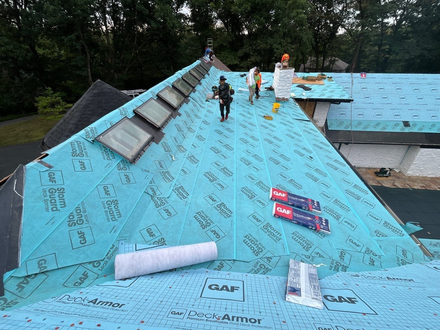 roofing crew installing synthetic underlayment and water shield on a residential roof