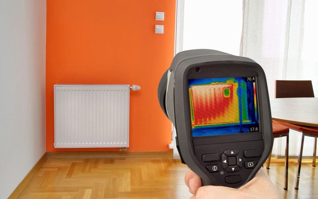 Restoration technician using thermal imaging to detect hidden moisture during water damage assessment in McKinney, TX home