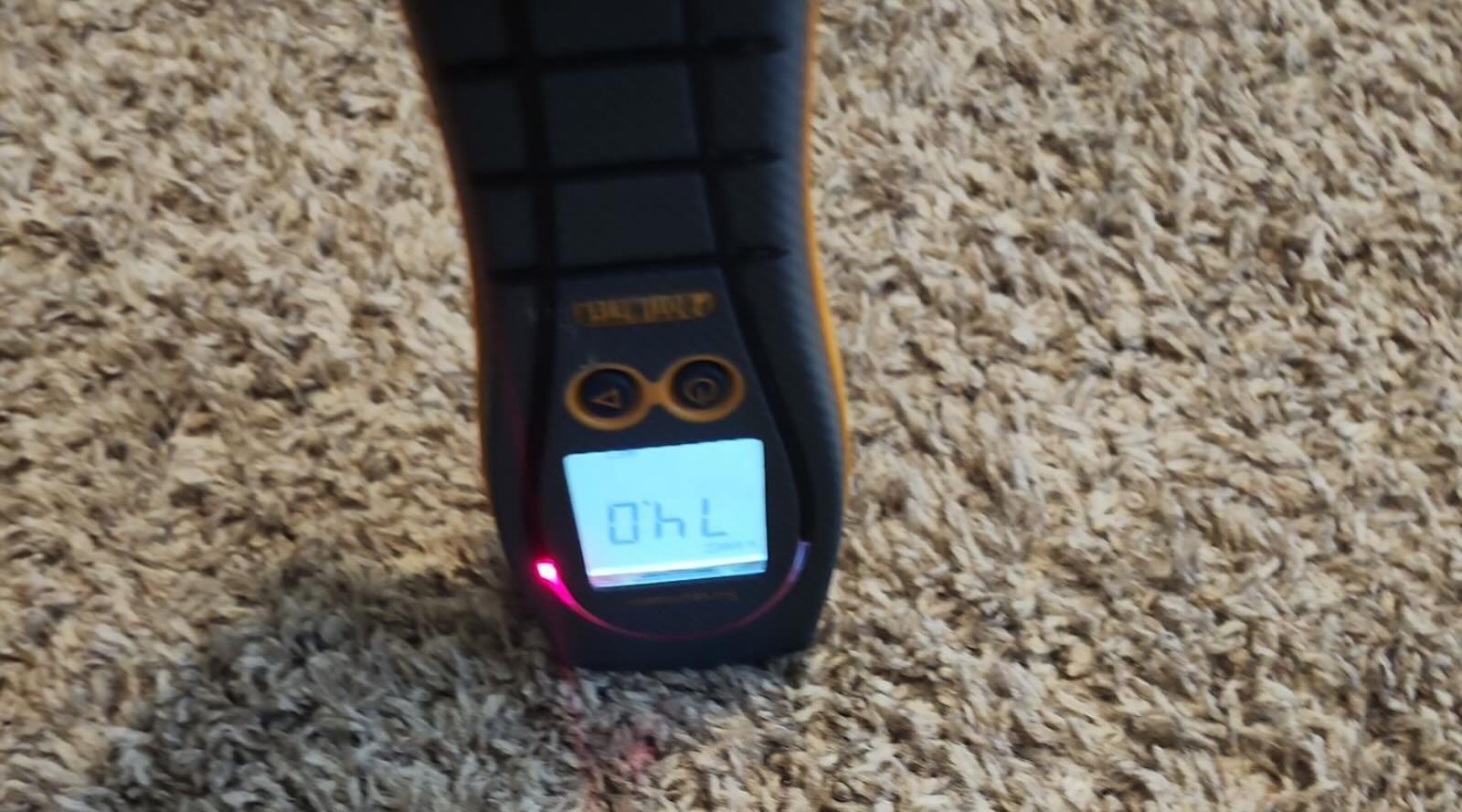 Moisture meter testing carpet for elevated moisture after water damage