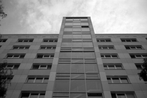 Hochhaus mit modernen Fenstern und grauem Himmel.