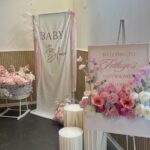 Schöne Baby Shower Dekoration mit Blumen und Willkommensschild.