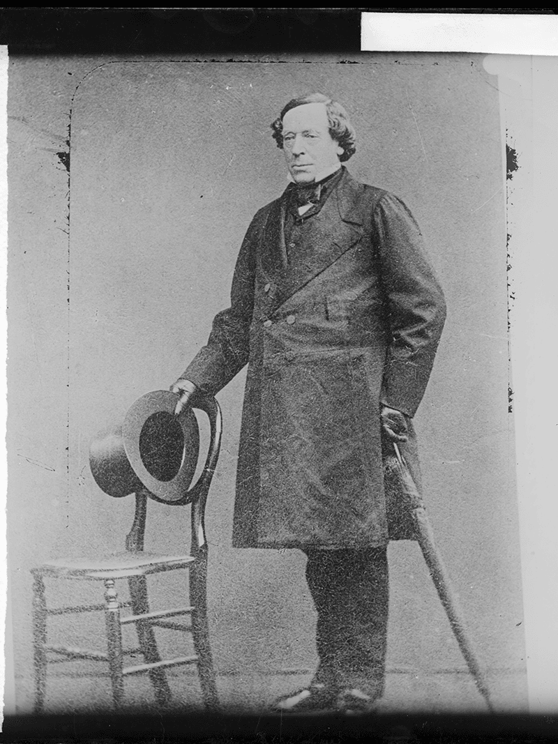 Image of George Augustus Robinson Standing next to a chair with his top hat in his hand.