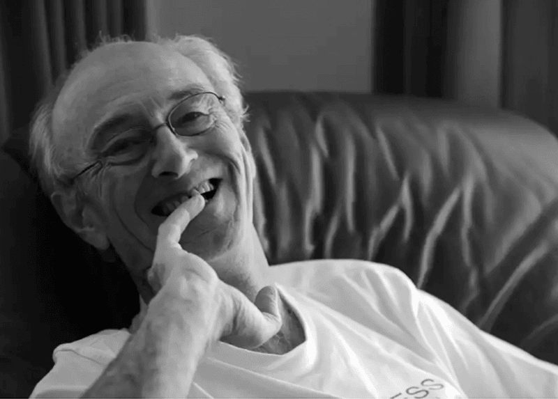 Image of Tim Thorne smiling at the camera while sitting on a couch.