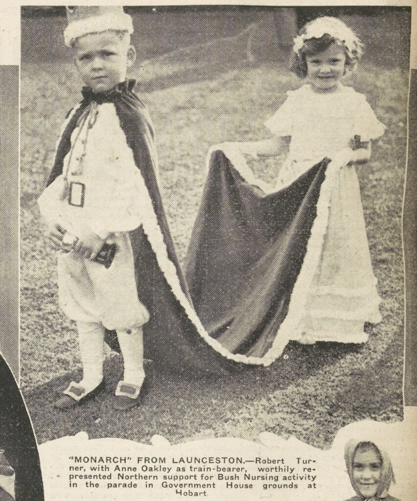 A snippet from a newspaper. A picture of a two young children, one dressed as a king holding a chalice, the other holding his cape off the ground.
