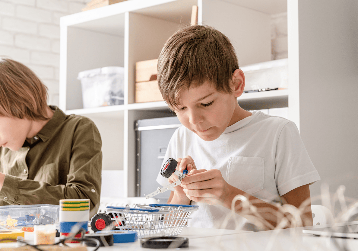 A primary school aged child building a toy car with a screwdriver.