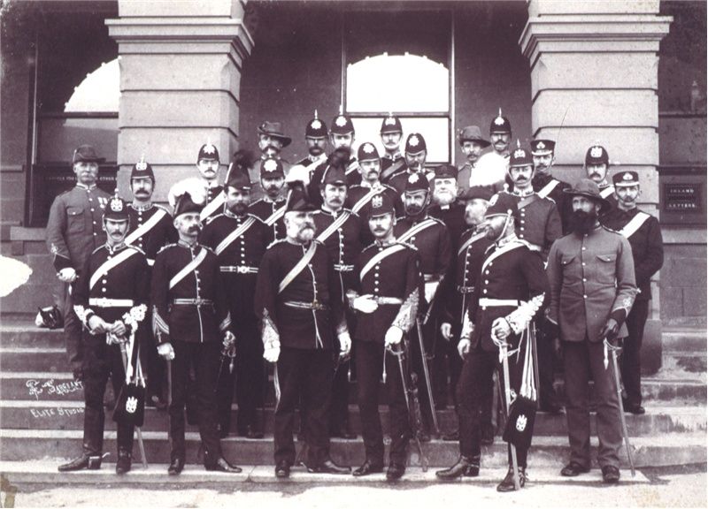 A group of men in officers' uniforms standing on the steps in front of a post office