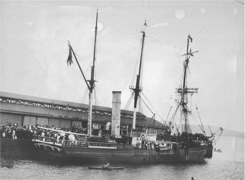 A black and white photo of a ship docked at a pier.