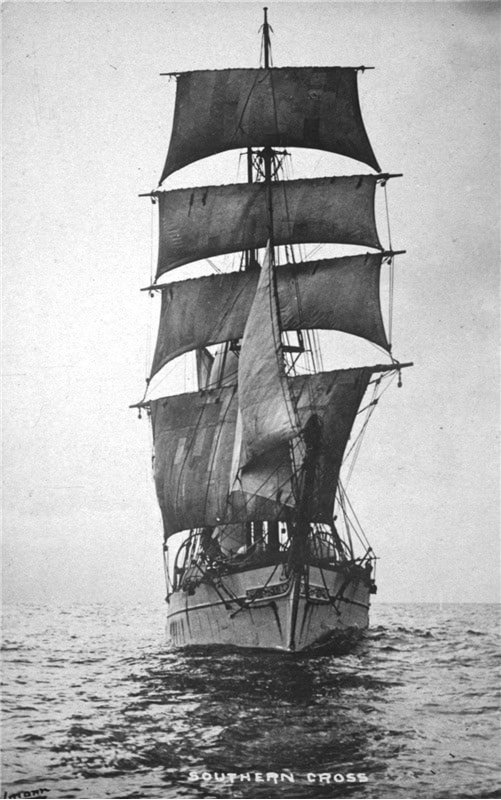 A black and white photo of a sailing ship on the water, as seen from the front.