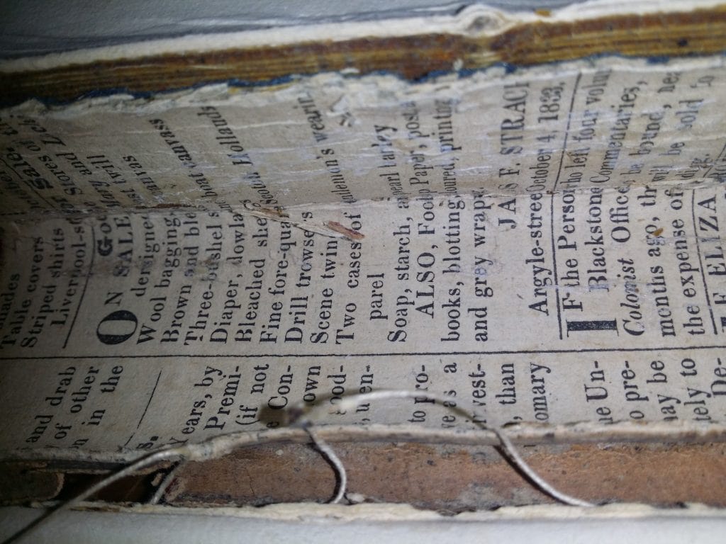 Old newspaper used as binding in a book.