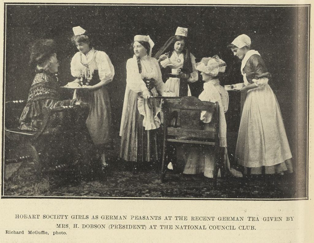 A snippet from a newspaper. Illustrated Tasmanian Mail 24/11/1910/. it is a photo of 6 women with trays of tea. Text at the bottom reads: "Hobart society girls as german peasants at the recent german tea given by Mrs. H. Dobson (President) at the national council club. Richard McGuffie, photo