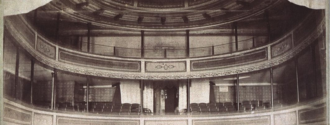 A black and white photo of the upper level of a theatre seating as seen form