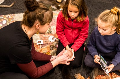 One adult and two children making ochre at a library