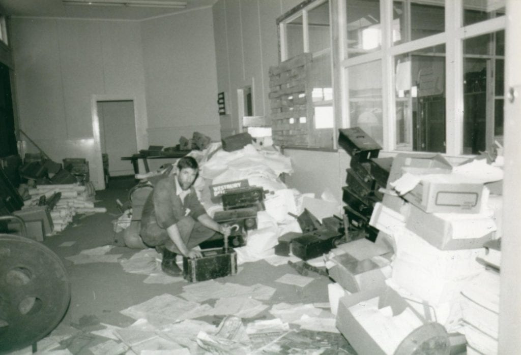 A man standing in a room sorting through old files.