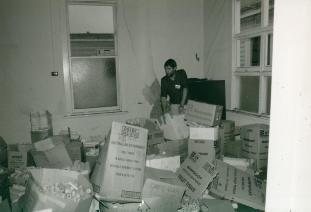 A man standing in a room looking though boxes