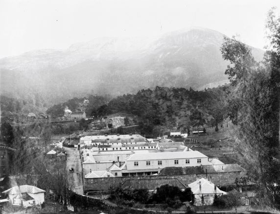 Several buildings connected together. Next to a road in a valley.