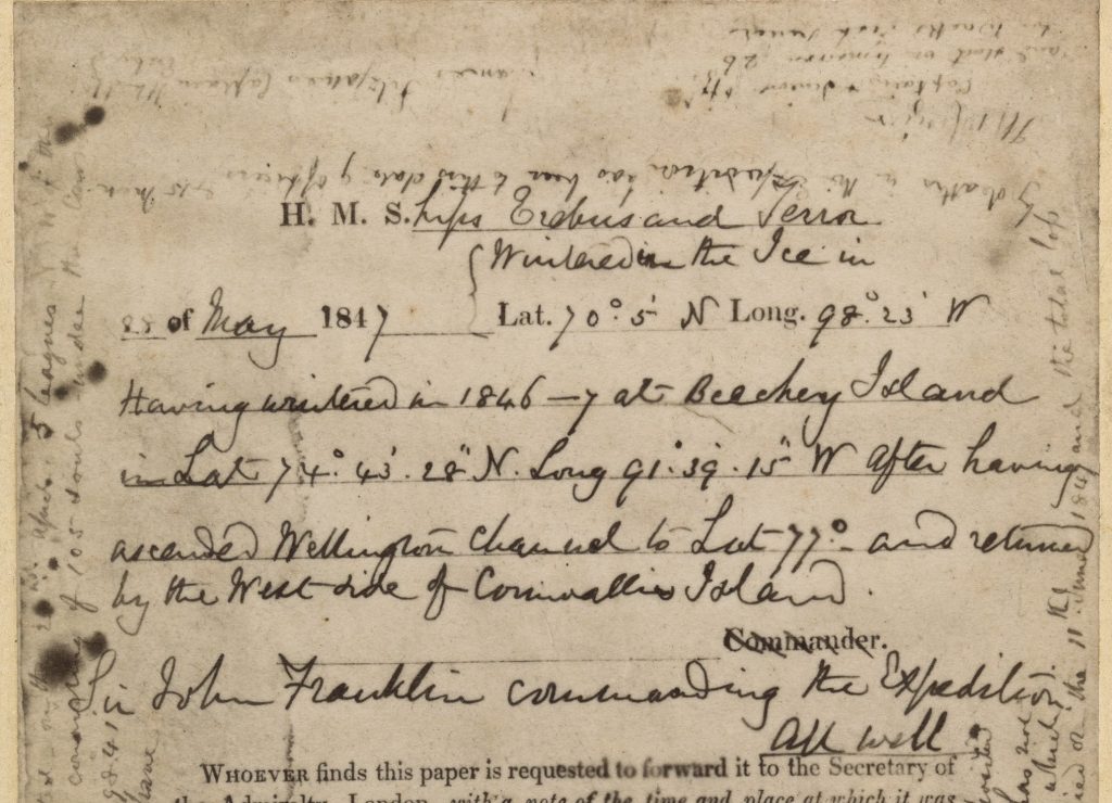 An old piece of paper detailing notes about 2 ships being wintered. It reads: H.M.S ships ‘Erebus’ and ‘Terror’ wintered in the Ice in lat. 70 05′ N., long. 98 23′ W. Having wintered in 1846–7 at Beechey Island, in lat. 74 43′ 28″ N., long. 91 39′ 15″ W., after having ascended Wellington Channel to lat. 77°, and returned by the west side of Cornwallis Island. Sir John Franklin commanding the expedition. All well.