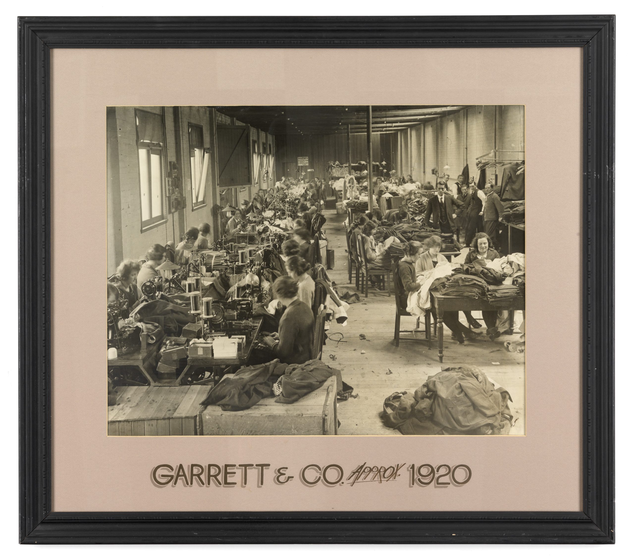 A framed photograph of Garrett & Co Clothing manufacturers. approximately 1920. Women in a room making clothing.
