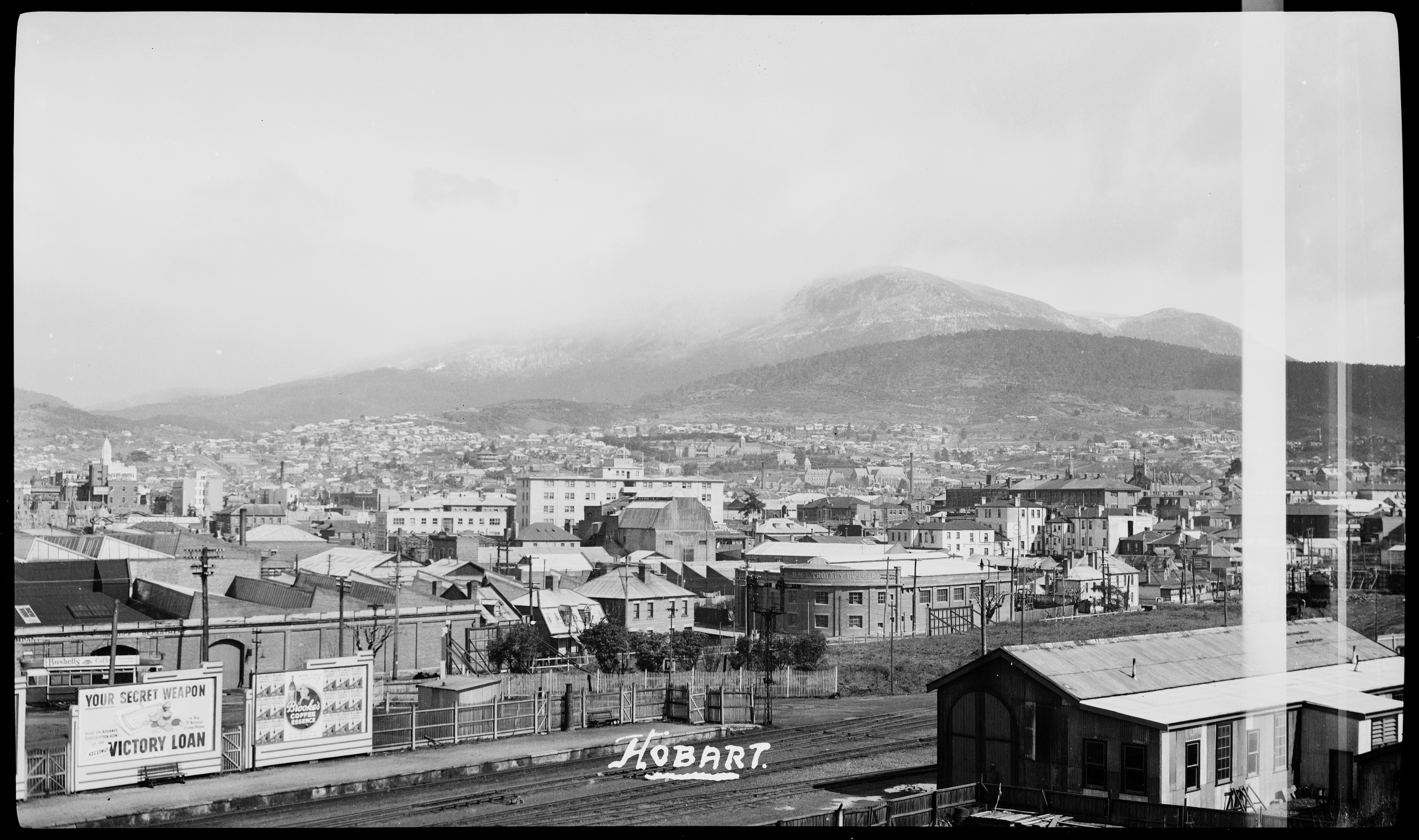 An old black and white photo of the town of Hobart, a railway station is in the foreground.