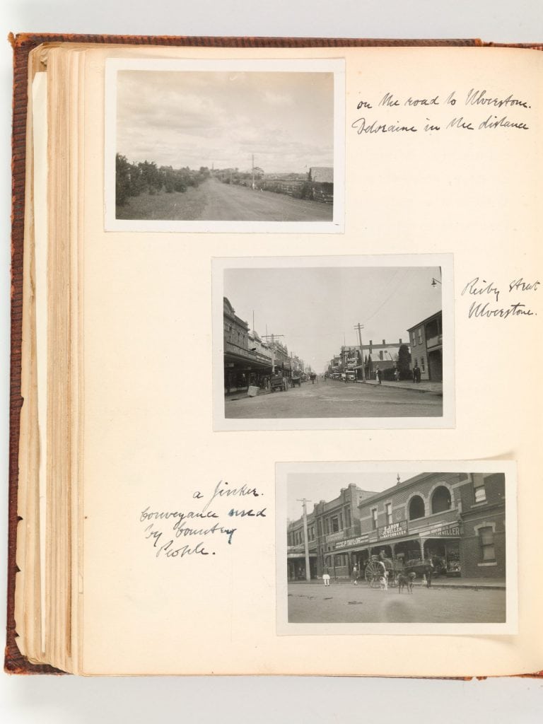 A page from an old photo album. there are 3 photos. 1 from a countryside road. and 2 are pictures of city streets.