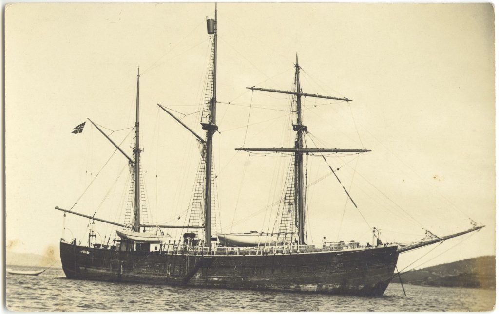 A black and white photo of a sailing ship on the water. its sails are furled.