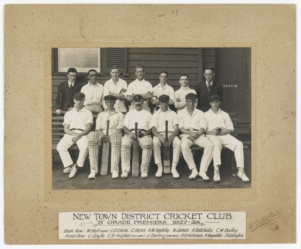 13 men in cricket uniformas. Text at the bottom reads: " New Town District Cricket Club 'B' Grade Premiers, 1927-28 Back row - W. hall(scorer) C. Oconnor, C. Ross, A.W. Appleby, N. James, A. Batchelor, C.W Bailey. Front Row- C.Coyle, C.B. Hughes(Vice. capt), J, Darling(Captain), D.G. Hickman, N. Reynolds, J. Eddington.