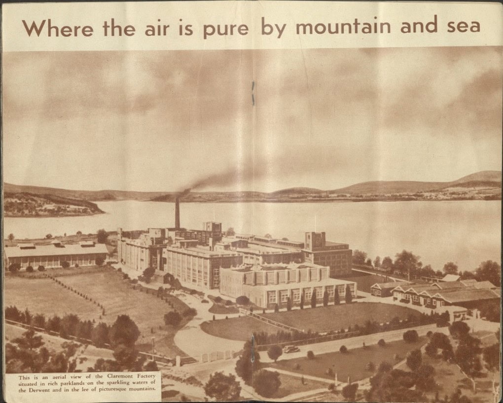 Anold black and white photo of an aerial view of the Claremont factory. Text at the top of the image reads: "Where the air is pure by mountain and sea" Text at the bottom left reads "This is an aerial view of the Claremont factory situated in rich parklands on the sparkling waters of the Derwent and in the lee of picturesque mountains."