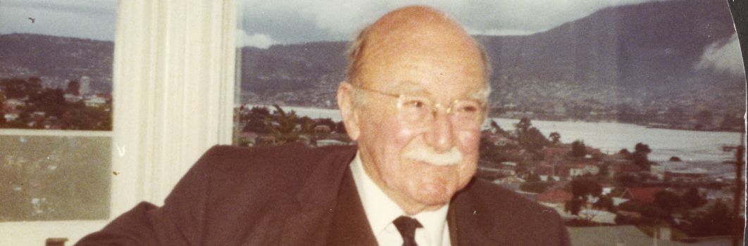 A photo of an old man inside in a suite in front of a window