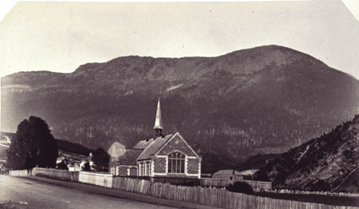 An old black and white photo of a picture of a school. seen from the other side of the road