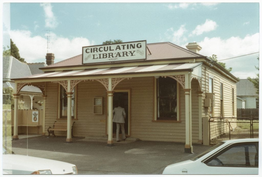 A colour photo of a building as seen from the street. the sogn on top of the building reads "circulating library"