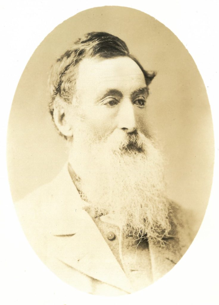 A black and white photo of a man with a white beard
