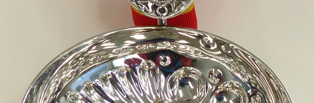 Tastevin. A silver cup with a red and yellow braided ribbon attached