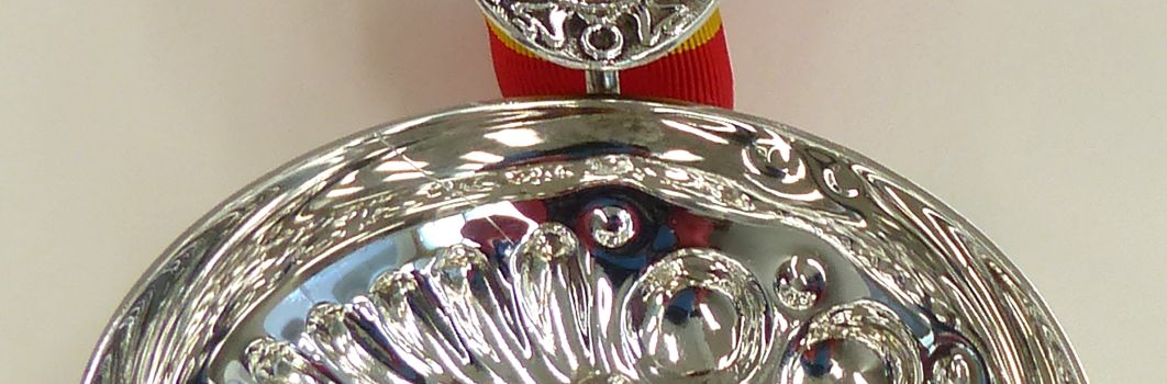 Tastevin. A silver cup with a red and yellow braided ribbon attached