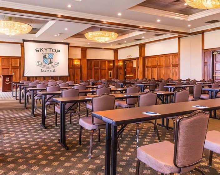 Many rows of tables and chairs in a meeting room