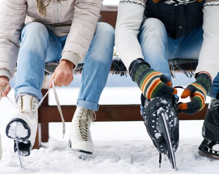 Two people putting on ice skates