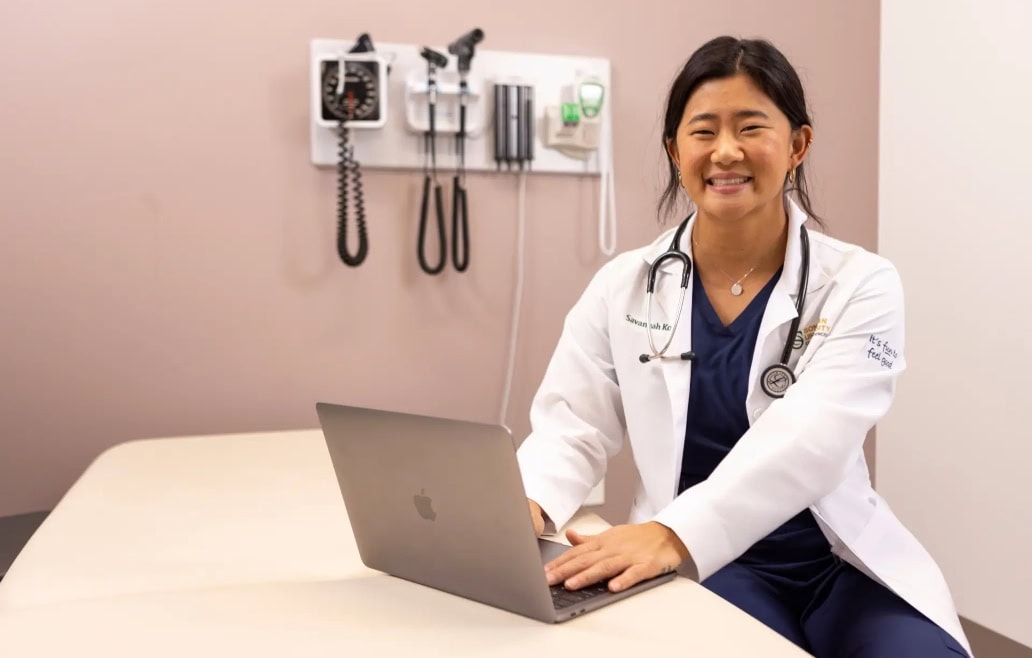 Woman in lab coat at Sonoran University working on a computer